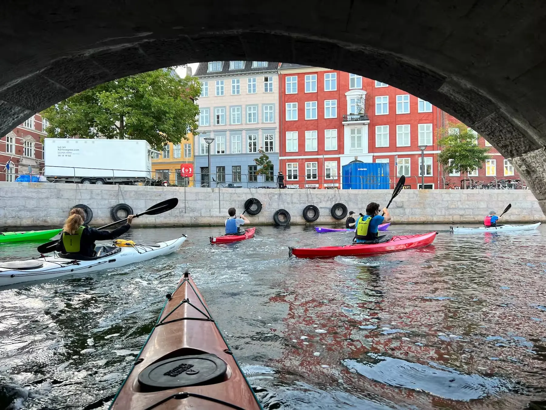 Kajaktur i Københavns kanaler med farverige kajakker under bro fra Kajakmanden